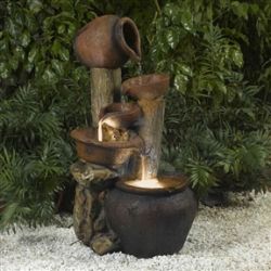 Clay Pot Style Indoor and Outdoor Fiberglass Illuminated Fountain next to bush
